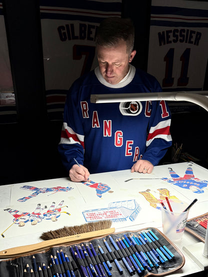 Person in a Rangers sweatshirt working on artwork with art supplies at a table.