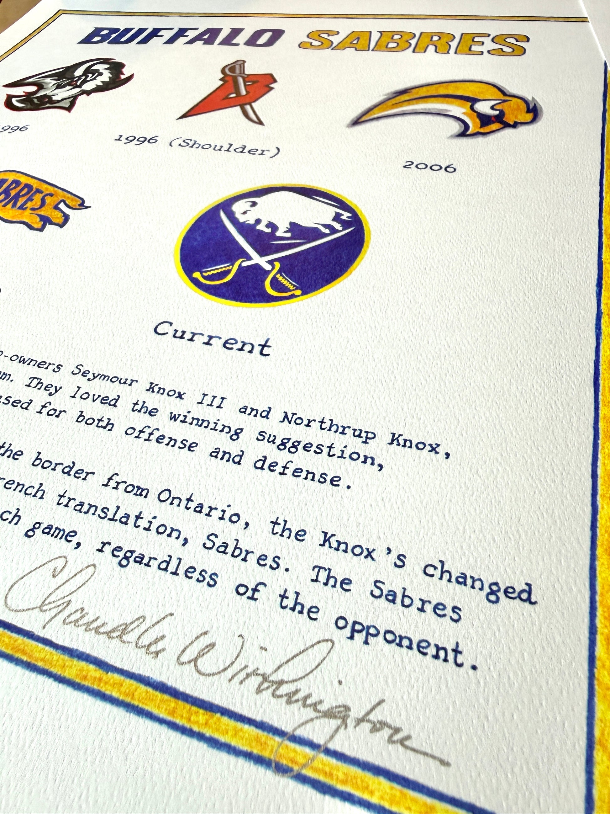History of the Buffalo Sabres logo evolution with text and artist's signature on a white archival paper
